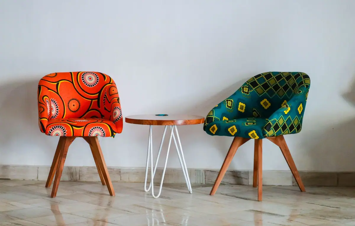 Two patterned armchairs and a small round table against a plain wall