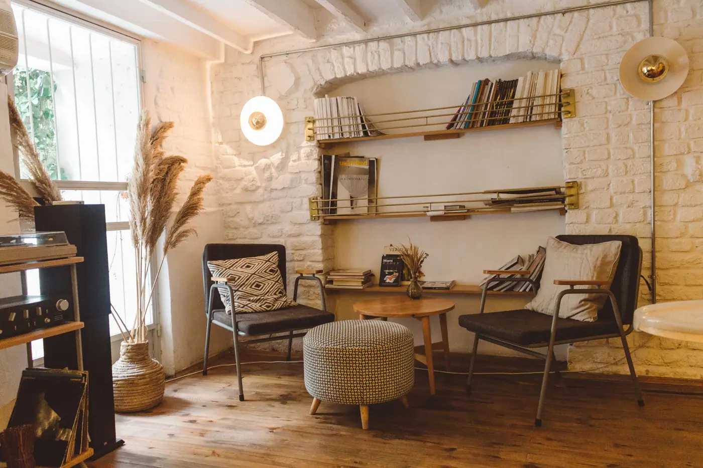 Two chairs, a stool, and wall-mounted shelves of books