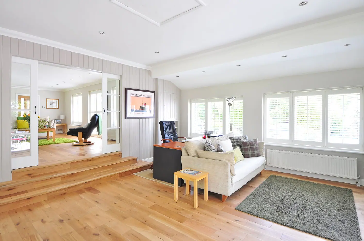 Living room with a step down, French doors, and a sofa along the far wall