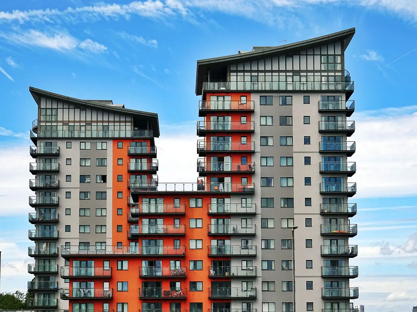 Two tall apartment buildings with orange and gray balconies